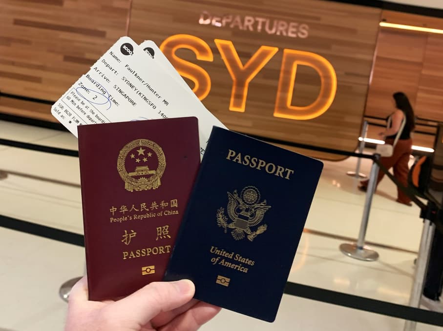 Our passports held up in front of the Sydney Departure sign